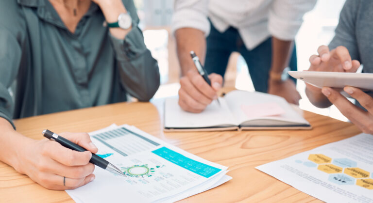 Business, group and hands for data on chart, analytics and graph for information in finance on desk. Teamwork, meeting and writing on document for financial strategy, planning and economy of market.