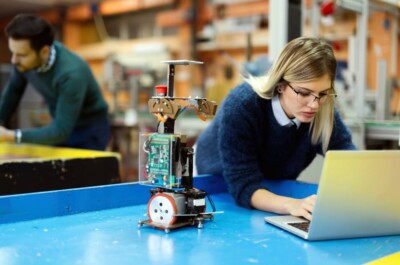oung beautiful female engineer testing and programming robot