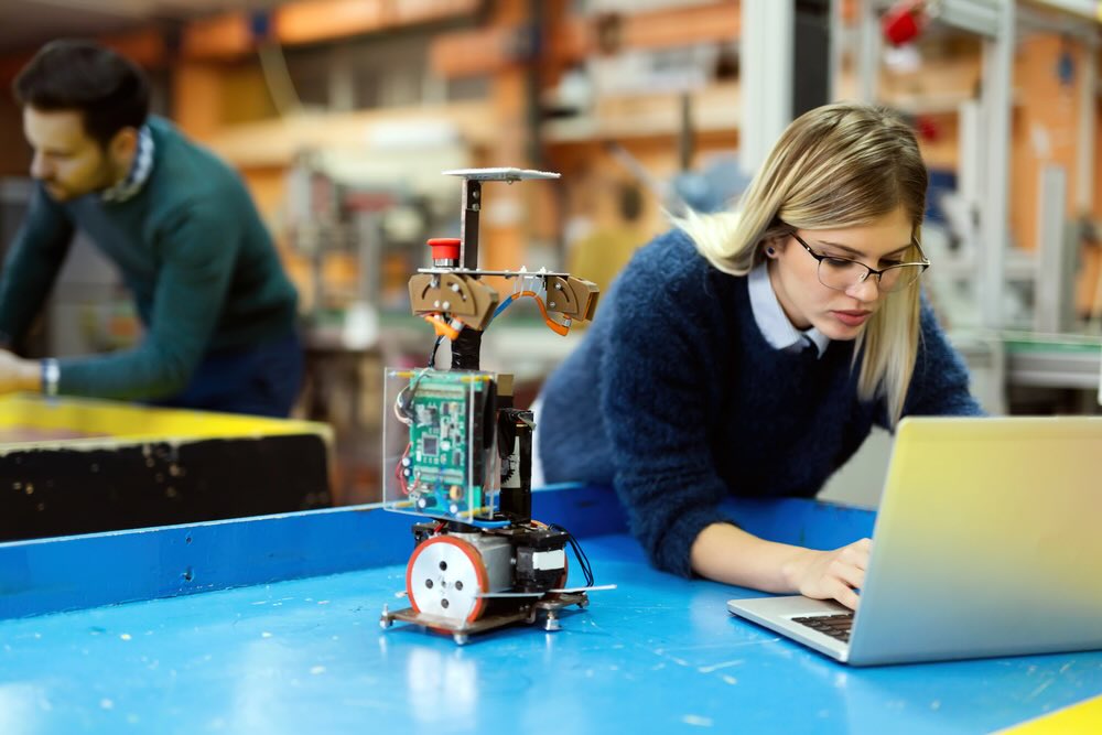 oung beautiful female engineer testing and programming robot